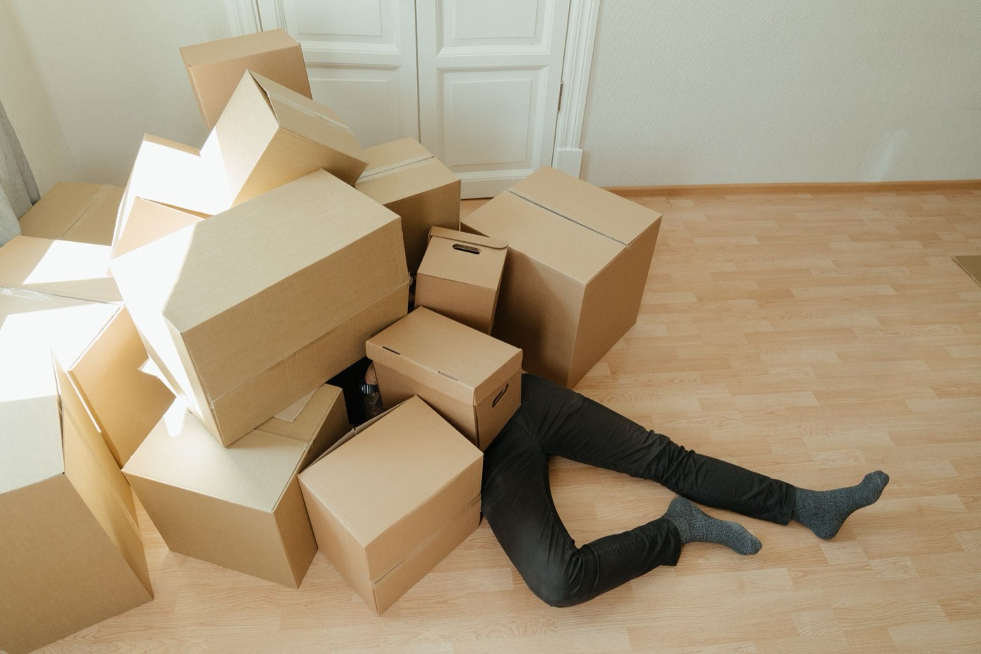 Una persona tirada en el piso, sepultada bajo una pila de cajas de cartón