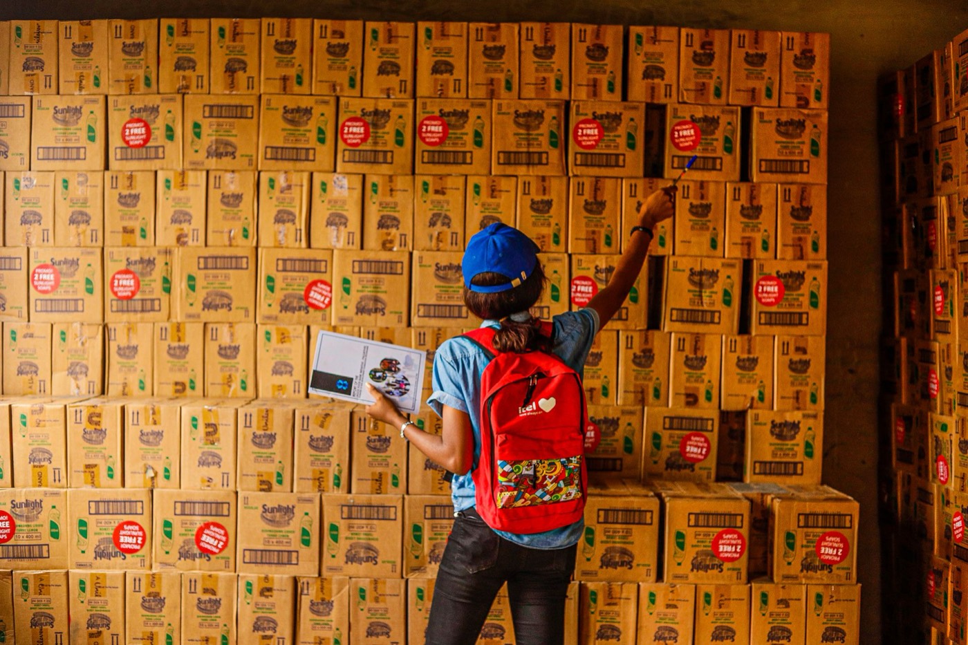 Una persona revisa una pared de cajas de inventario con una lista en la mano